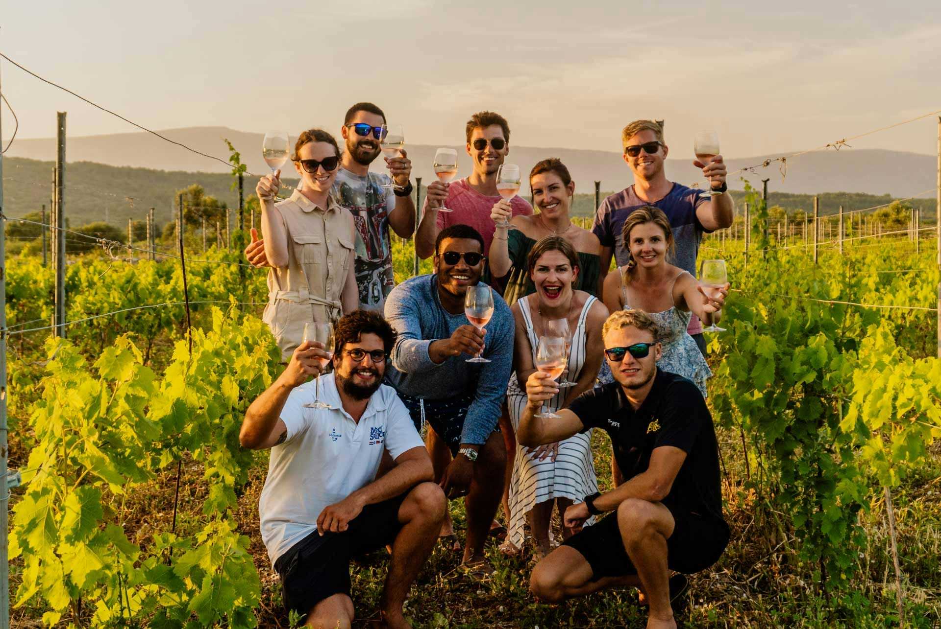 Group of people pose for a photo amongst some vines