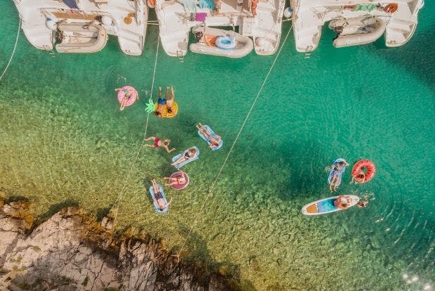 Guests floating behind boats in clear water