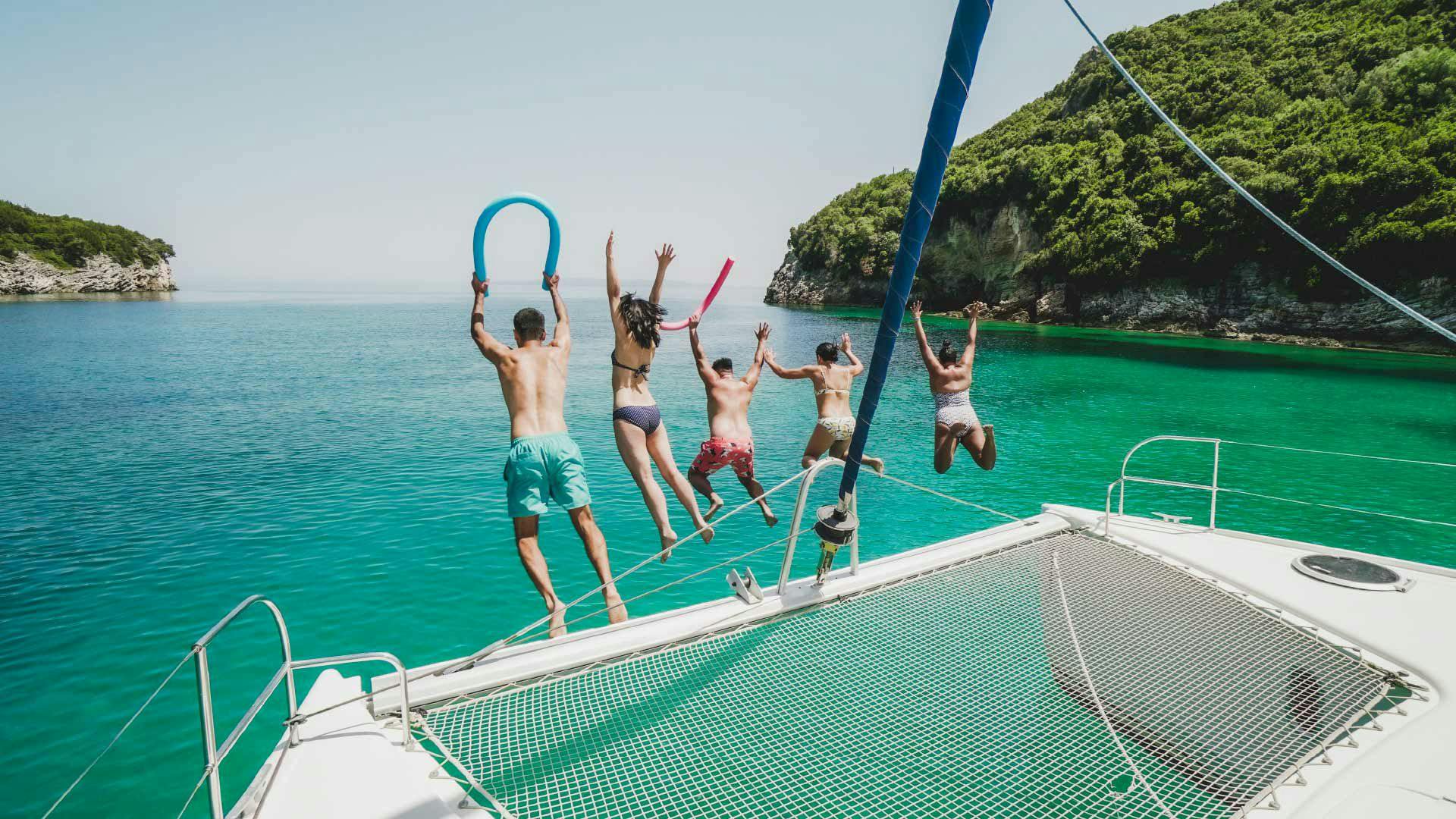 Guests jump off a MedSailors catamaran