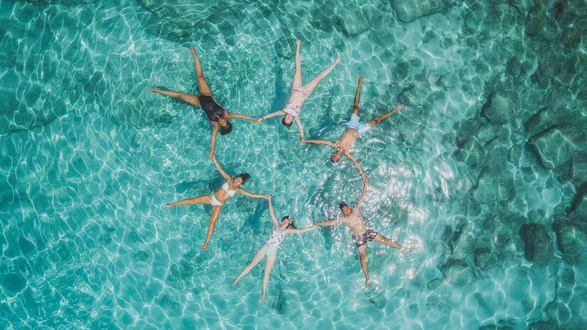 Group of people float in clear blue water in Greece