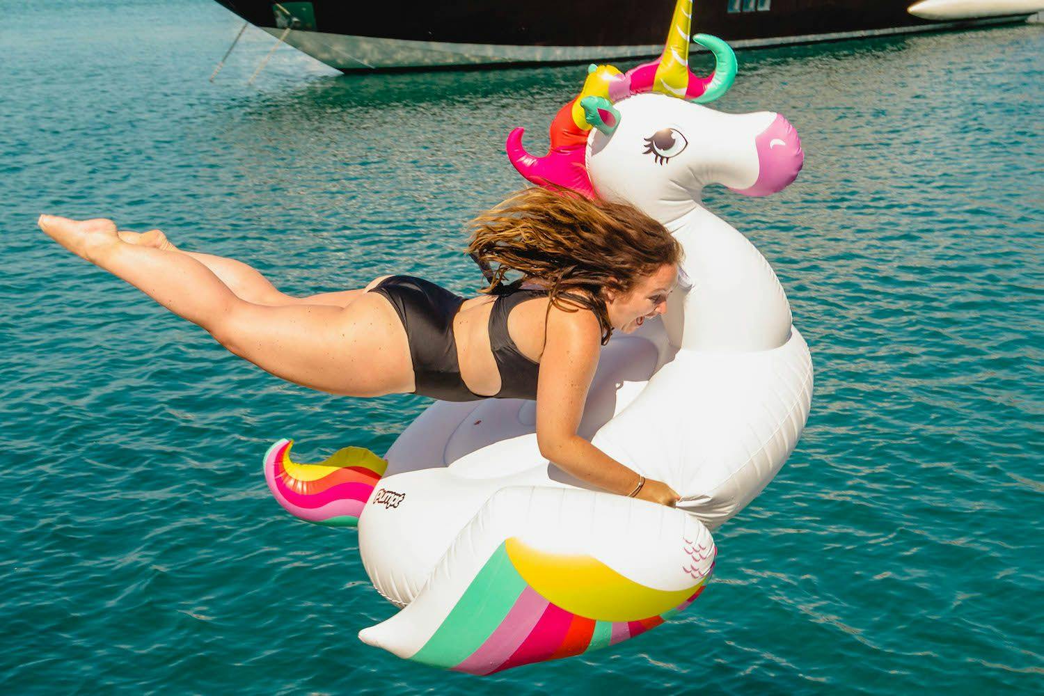 Photo if a girl jumping into water with an inflatable unicorn floatie. Photo by Ryan Brown of Lost Bly Memoirs
