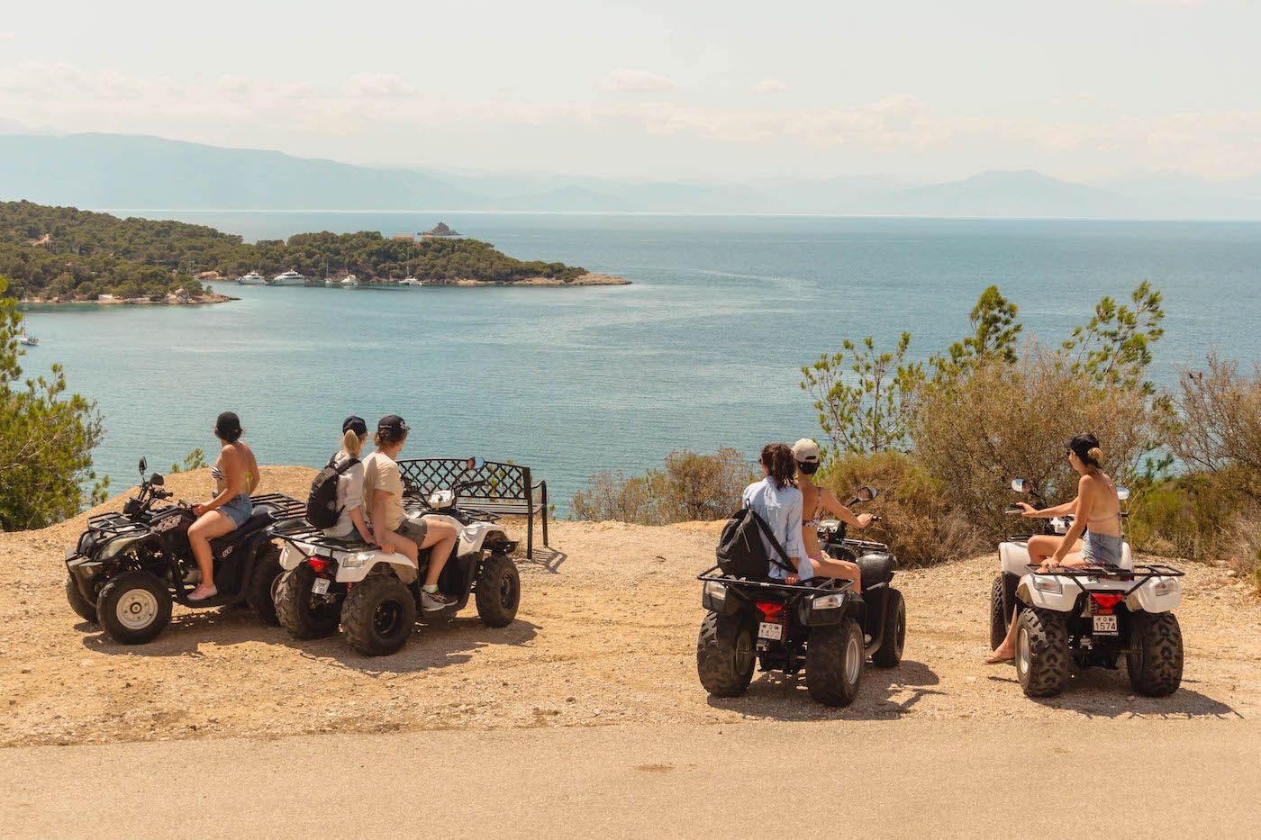 Photo of quad bikes with people on a cliffside in Spetses Greece. Photo by Ryan Brown of LostBoyMemoirs.com