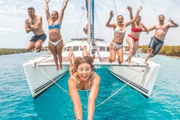 Group of people jump off catamaran whilst taking a selfie