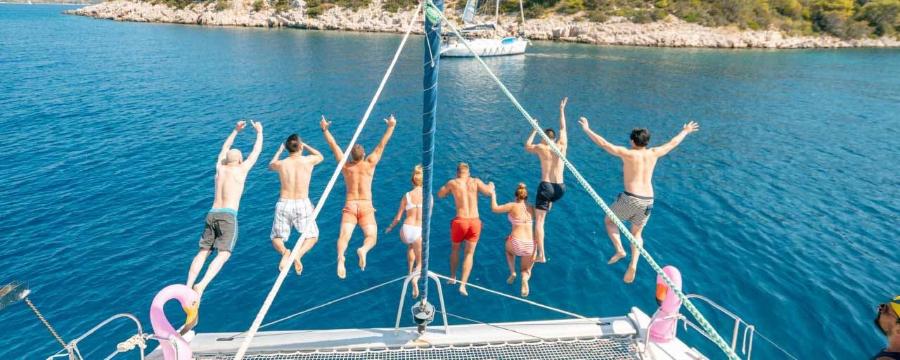 Group of MedSailors guests jump off a yacht into the sea
