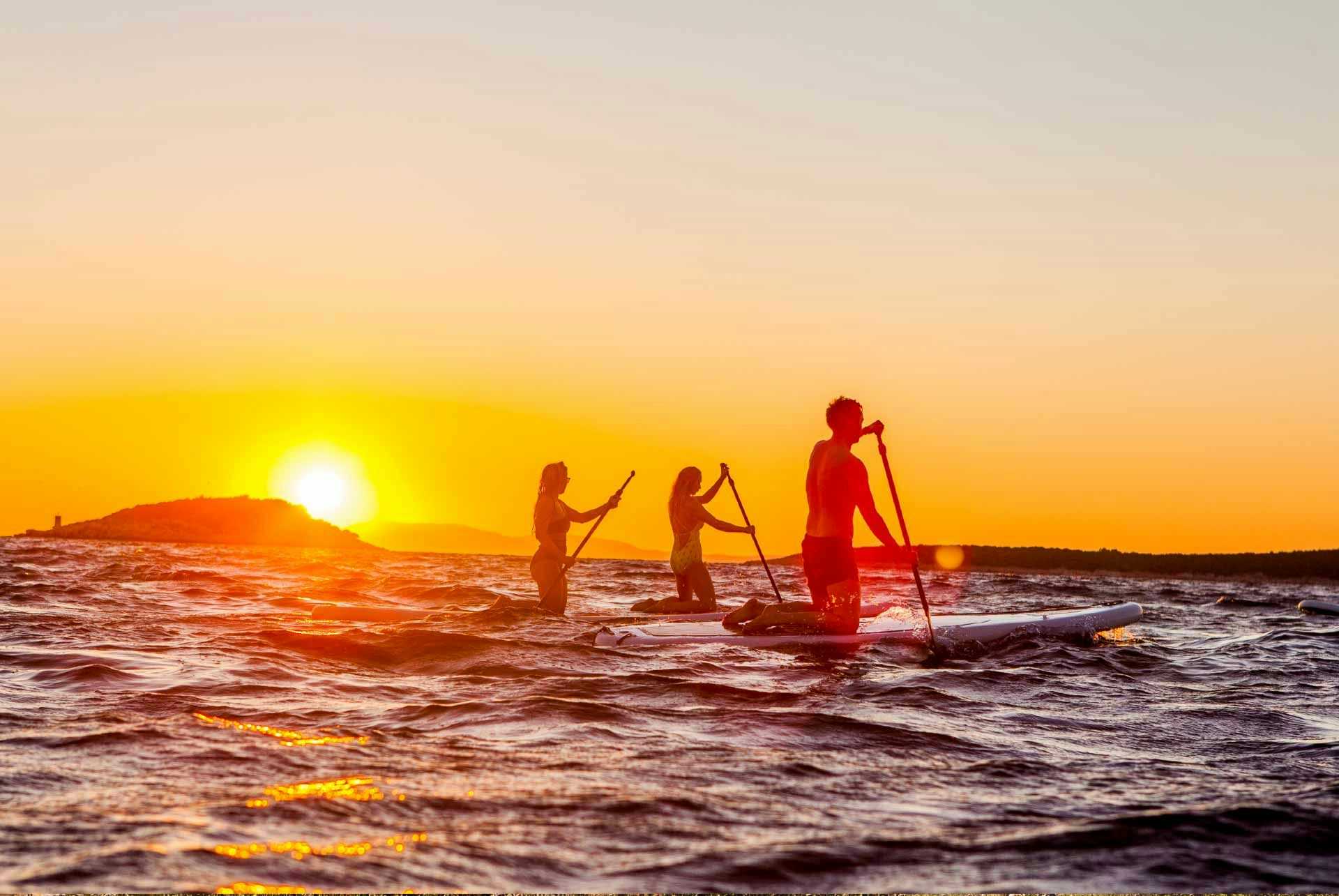 Group of friends paddleboarding at sunset in Turkey