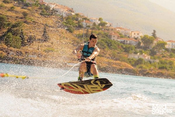 4 Reasons to Visit Poros Greece - Male on wakeboard in Poros Greece waterspouts jumping a wake. Photo by Ryan Brown of LostBoyMemoirs.com