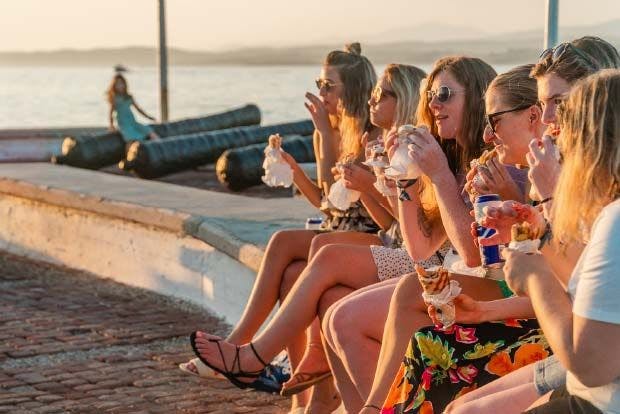 Young women eat gyros on waterfront in Greece