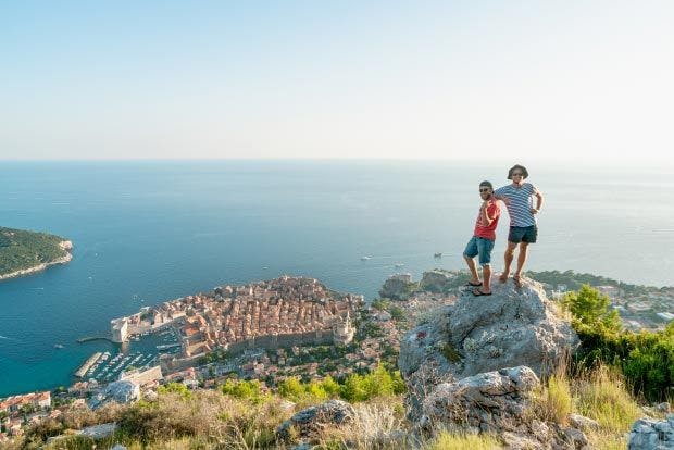 Two people hike above Dubrovnik Old Town in Croatia