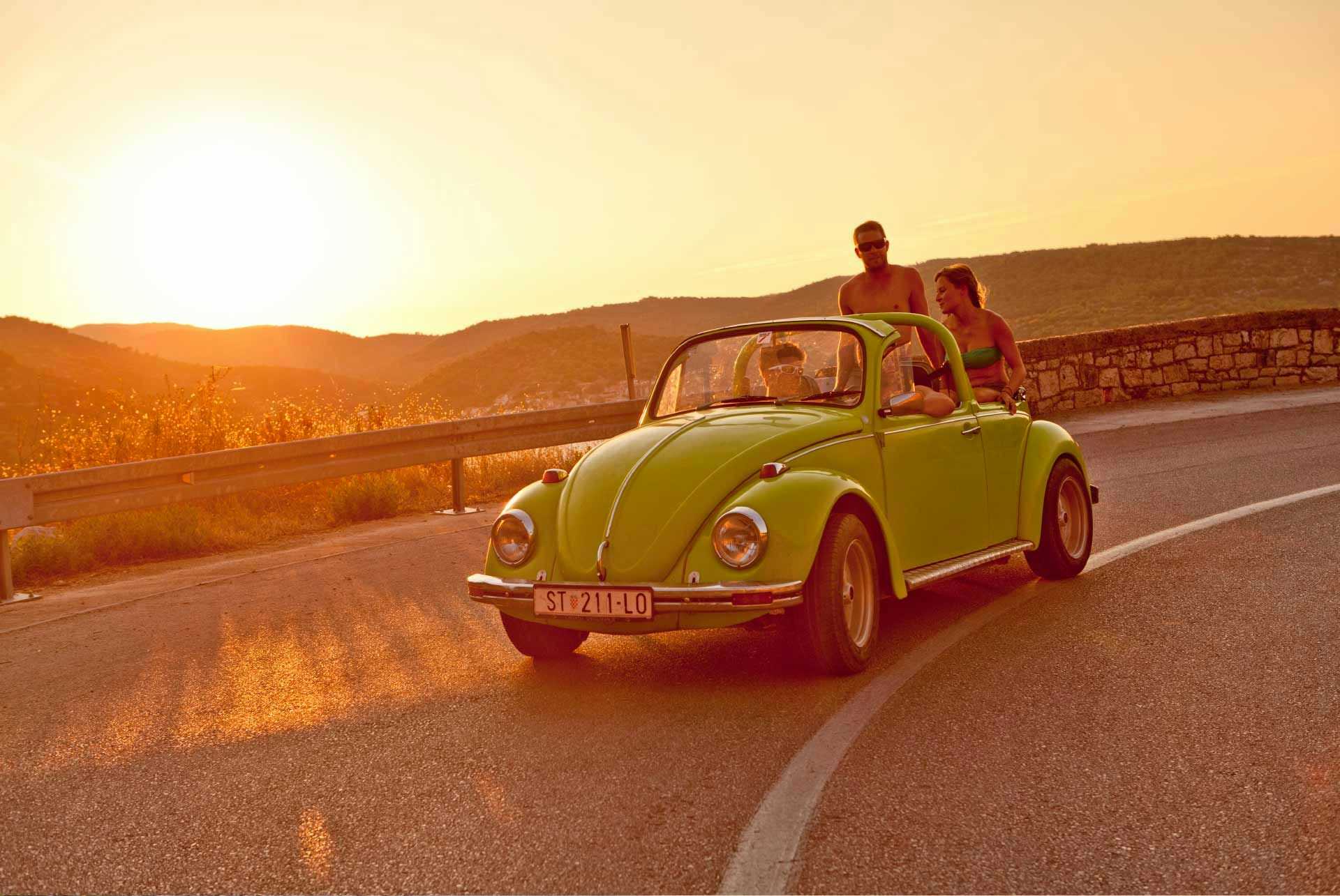 Group driving a convertable car in Vis at sunset